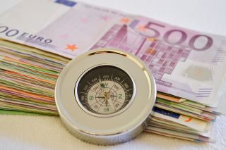 © Martina Wendt - stock.adobe.com Foto: Geldscheine mit eine Kompass davor